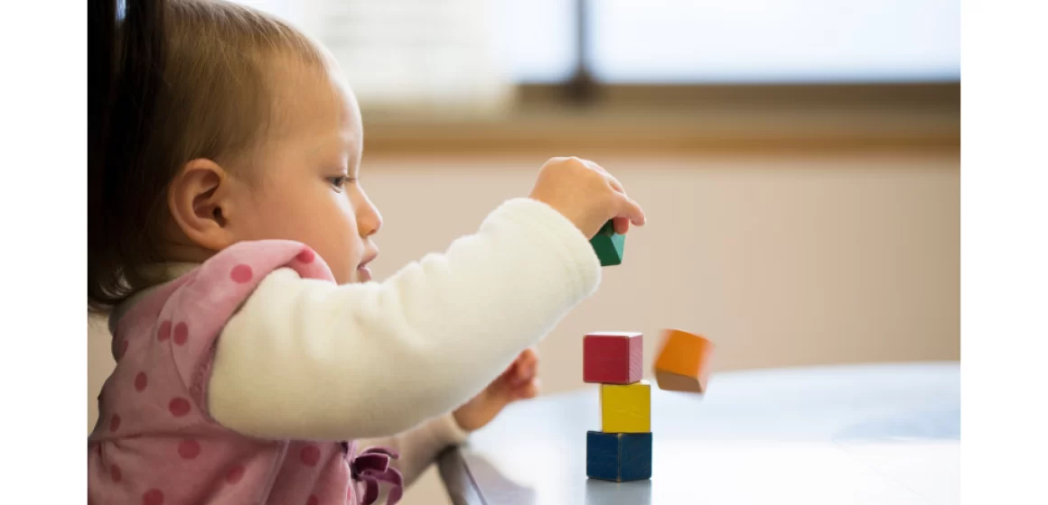 A baby is playing with blocks at a table.