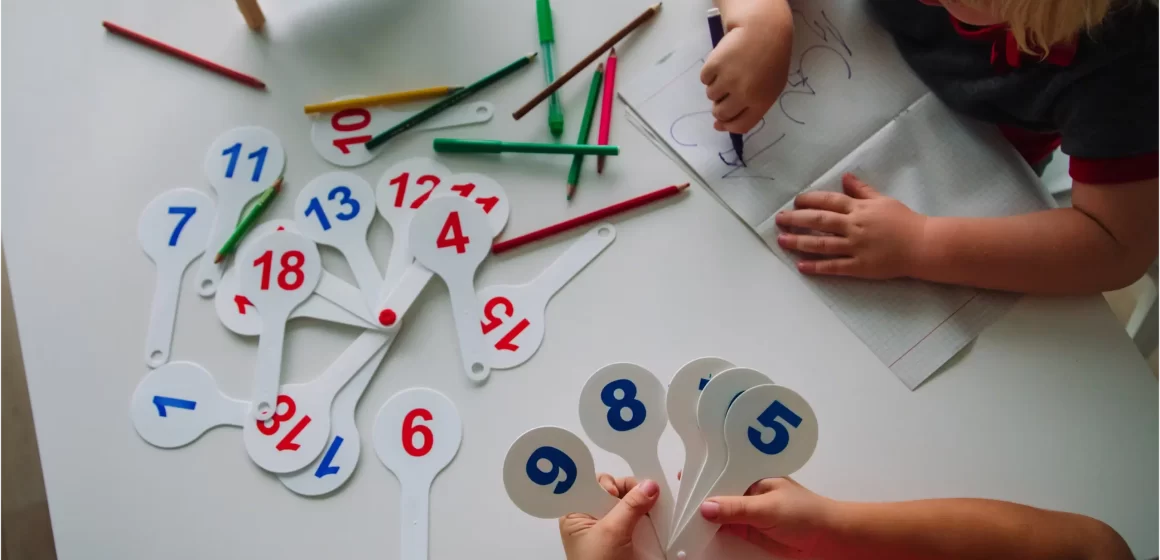 Children playing with numbers and abacus at a table.